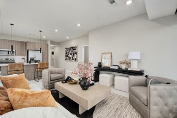 Birmingham apartment for rent - A modern living room with a white sofa, a wooden coffee table, and a black and white abstract painting on the wall.