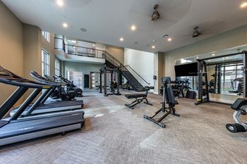 A gym with treadmills and other exercise equipment and a staircase