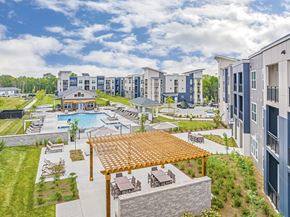 Nashville apartment for rent - A large outdoor swimming pool surrounded by a wooden deck and lounge chairs at The Percy Apartments, Tennessee, 37214