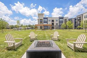 Nashville apartment for rent - A fire pit sits in the middle of a grassy area with four chairs around it at The Percy Apartments, Tennessee
