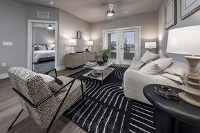Winter Haven apartment for rent - A well-lit bedroom with a large bed, a chair, and a coffee table at The Waverly at Winter Haven Apartments, Florida