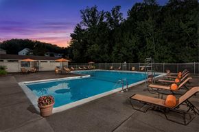 Reston apartment for rent - a swimming pool with chairs around it at sunset