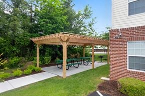 Martinsburg townhouse for rent - A wooden pergola with green benches is in front of a brick building.