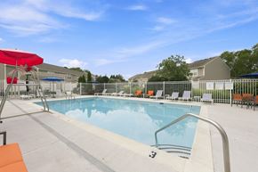 Great Mills apartment for rent - A swimming pool with a red umbrella and lounge chairs.