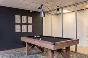 Richmond apartment for rent - A pool table with a black cloth and white balls is in the center of the room.