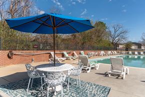 Newport News apartment for rent - a poolside patio with tables and chairs and an umbrella