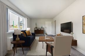Hyattsville apartment for rent - A living room with a blue couch, a wooden coffee table, and a flat screen TV mounted on the wall.