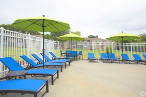 Portsmouth apartment for rent - a group of blue lounge chairs with green umbrellas in front of a white fence