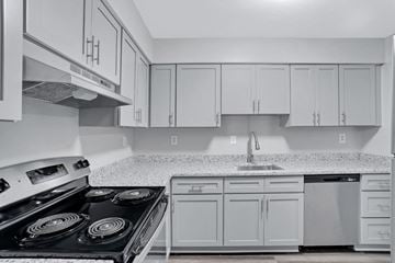 Portsmouth apartment for rent - A kitchen with white cabinets and a black stove top.