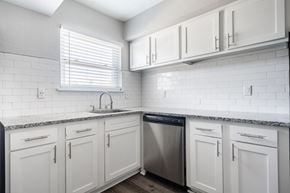 Newport News apartment for rent - A kitchen with white cabinets and a black dishwasher.