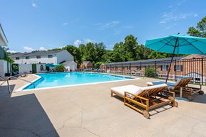 Charlottesville townhouse for rent - A pool with a sun lounger and umbrella in front of a building.