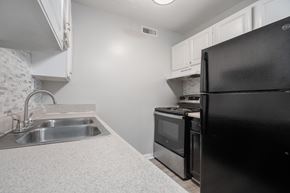 Newport News apartment for rent - A black refrigerator sits in a kitchen next to a stove and sink.