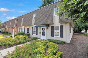 Hopewell townhouse for rent - A building with a grey roof and white walls with a garden in front.