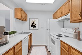 Charlottesville apartment for rent - A kitchen with white appliances and wooden cabinets.