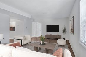 Charlottesville apartment for rent - A living room with a white couch, a wooden coffee table, and a flat screen TV mounted on the wall.