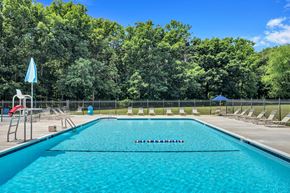 Gaithersburg apartment for rent - a swimming pool with chaise lounge chairs and trees in the background