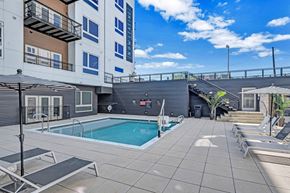 Richmond apartment for rent - a pool with lounge chairs and a building in the background