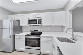 Fredericksburg townhouse for rent - a kitchen with white cabinets and stainless steel appliances