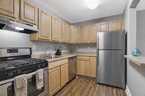 Bladensburg apartment for rent - A kitchen with wooden cabinets and a stainless steel refrigerator.