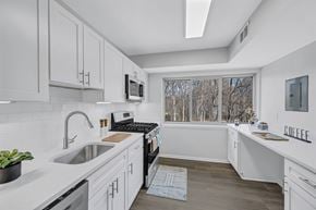 Reston apartment for rent - A kitchen with white cabinets and a window overlooking trees.
