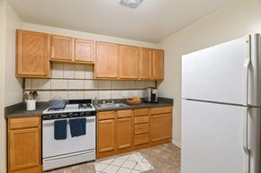 Hyattsville apartment for rent - a kitchen with white appliances and wooden cabinets and a refrigerator