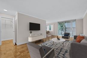 Bethesda apartment for rent - A living room with a grey couch, a white coffee table, and a flat screen TV mounted on the wall.