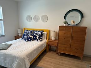 Richmond apartment for rent - A bedroom with a bed, nightstand, and a dresser with a mirror on top.