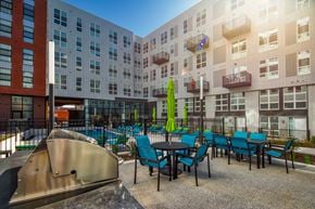 Richmond apartment for rent - a patio with blue chairs and tables in front of an apartment building