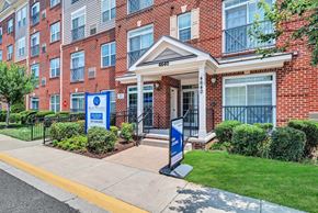 Woodbridge apartment for rent - the front entrance of a brick building with a porch and lawn