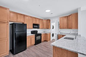 Woodbridge apartment for rent - a kitchen with wooden cabinets and a black refrigerator