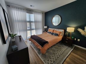 Richmond apartment for rent - A bedroom with a bed, nightstand, and a round mirror on the wall.