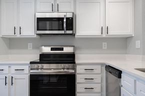 Great Mills apartment for rent - A modern kitchen with white cabinets and black appliances.