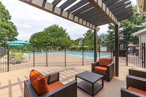 Reston apartment for rent - A patio with a pool in the background and a black table and chairs.