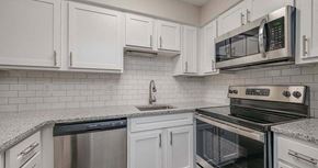 Newport News apartment for rent - a kitchen with white cabinets and a stove and a microwave