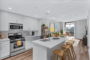 Reston apartment for rent - an open kitchen and living room with white cabinets and a marble counter top