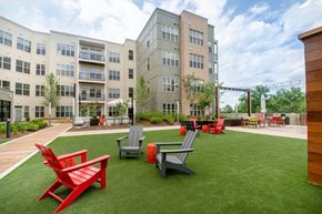 Washington apartment for rent - a courtyard with red chairs and lawn chairs in front of an apartment building