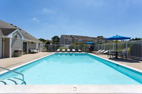 Great Mills apartment for rent - A swimming pool surrounded by a white fence and blue umbrellas.