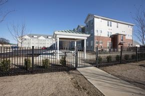 Memphis apartment for rent - A white building with a green roof is behind a black fence.