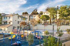 Los Angeles apartment for rent - A playground with a blue slide and a yellow slide in front of apartment buildings.