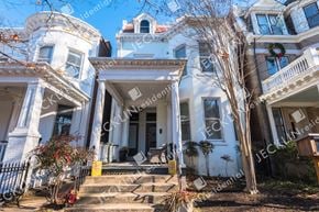 Richmond house for rent - A white house with a black fence and a yellow trash can in front.