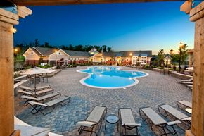 Concord apartment for rent - an outdoor pool with lounge chairs and tables at dusk