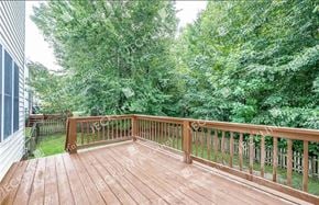 Henrico house for rent - A wooden deck with a railing and trees in the background.