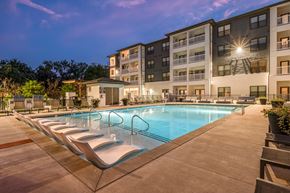 Nashville apartment for rent - a swimming pool with chaise lounge chairs and a building in the background