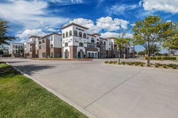 Grand Prairie apartment for rent - A large building with a white and brown facade is surrounded by a grassy area and a concrete driveway.
