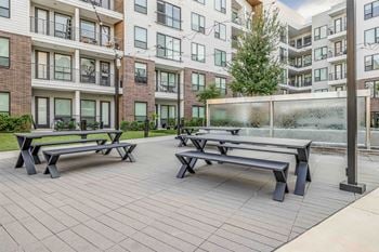 North building courtyard with grilling and picnic area, swings, fire pit with cozy seating, and yard game area