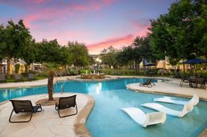 Austin apartment for rent - A pool area with a palm tree and lounge chairs.