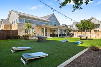 Outdoor poolside game area with corn hole and ping pong tables