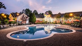 Concord apartment for rent - A large outdoor swimming pool surrounded by a brick patio and lounge chairs.