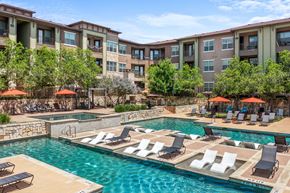 Georgetown apartment for rent - A large swimming pool with lounge chairs and umbrellas in front of apartment buildings.