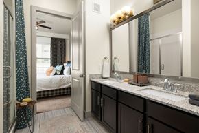 Georgetown apartment for rent - A bathroom with a mirror, sink, and a bedroom with a bed and a window.